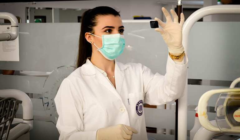 Investigadora observando una muestra con mascarilla y guantes